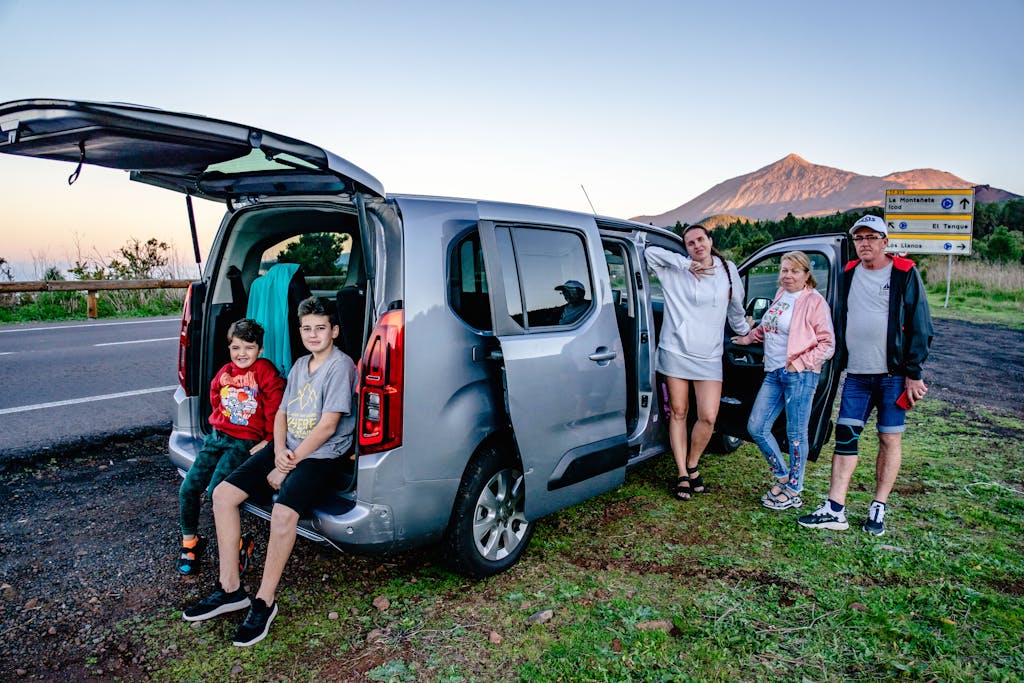 Imagen actual: A family enjoys a scenic road trip by Mount Teide, Spain, with a van parked by the roadside.
