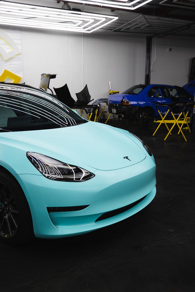Imagen actual: Modern turquoise Tesla car parked in a garage with overhead lights.