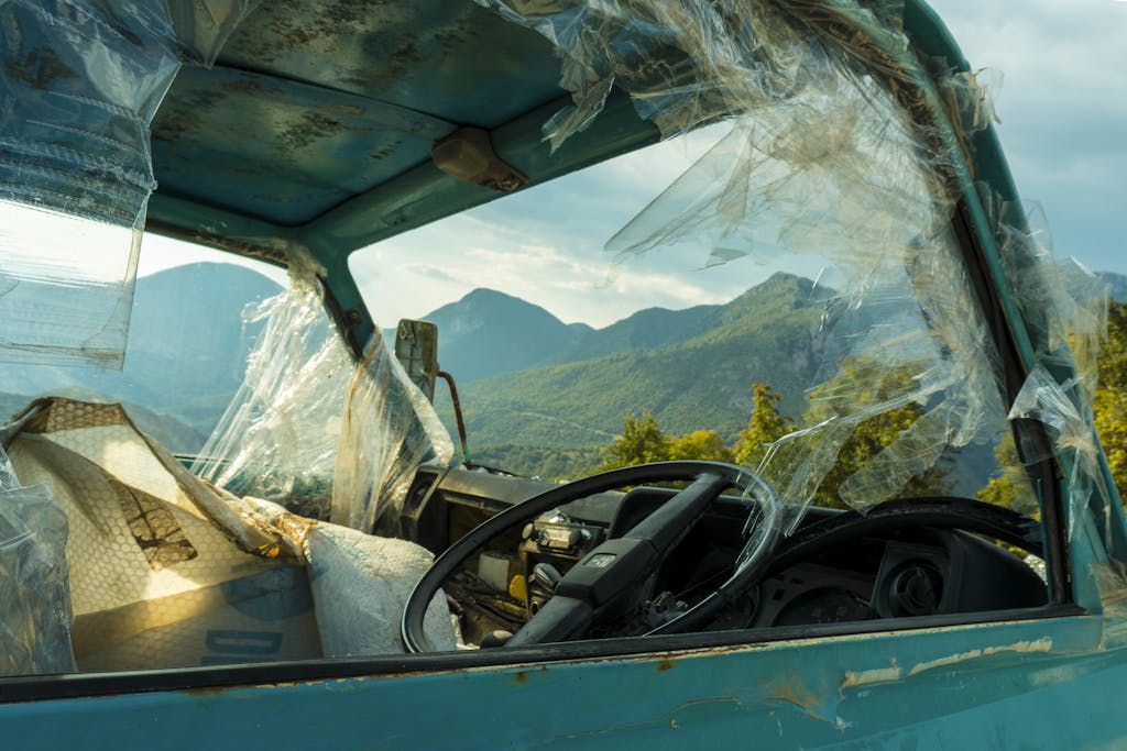 Imagen actual: Old rusty truck with broken windows in front of mountain landscape, symbolizing decay.