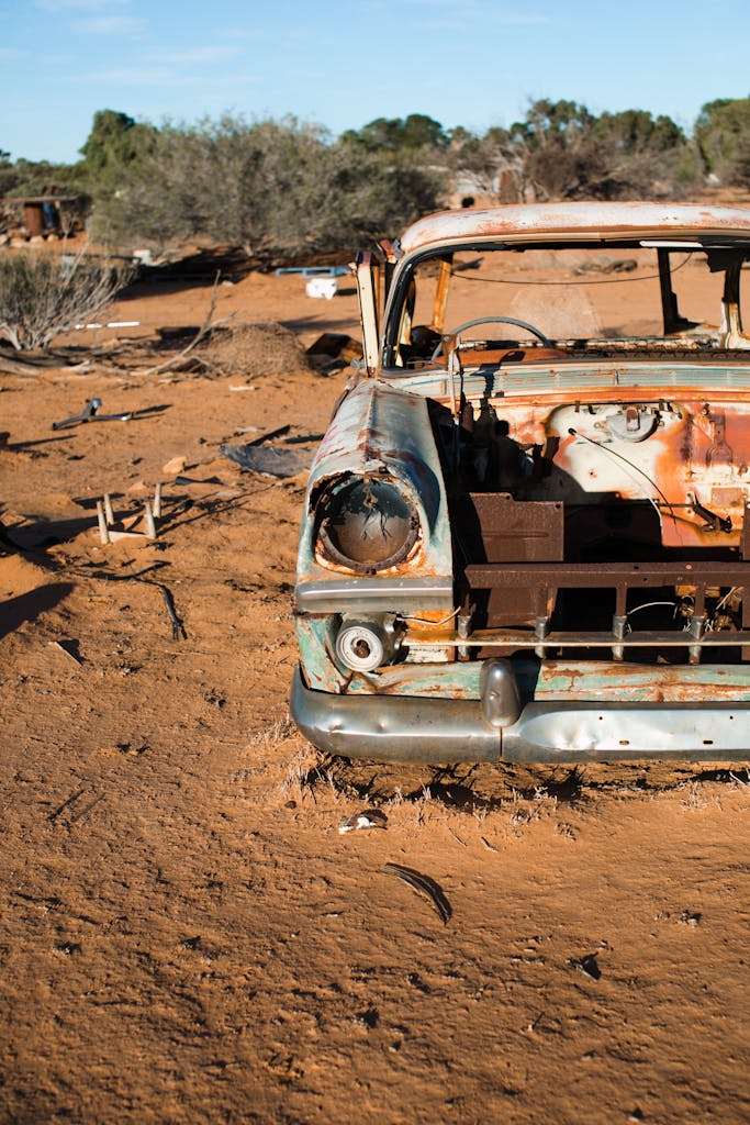 Imagen actual: A rusty, abandoned vintage car in a dry desert landscape, symbolizing decay.