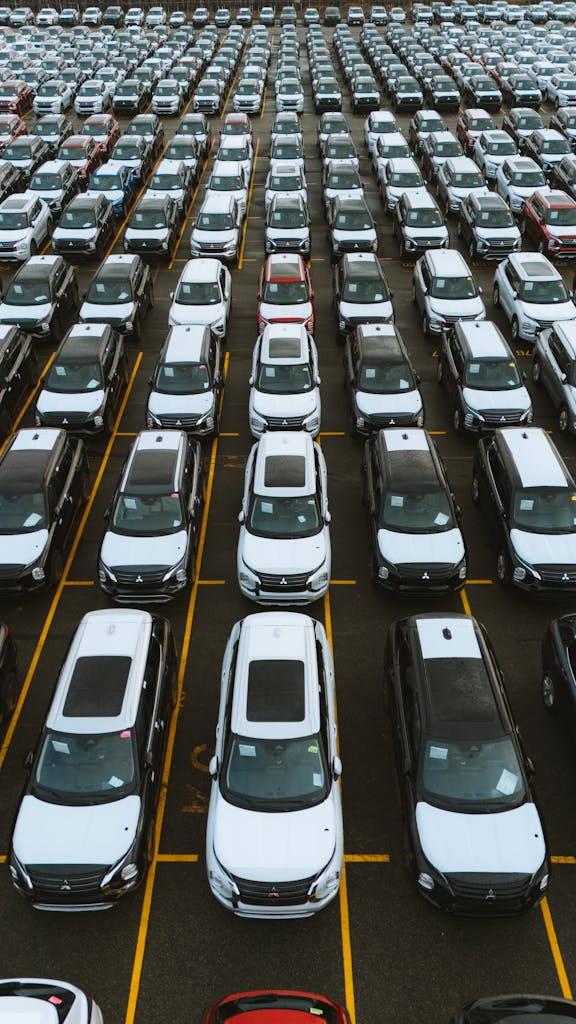 Imagen actual: Aerial view of numerous cars in a parking lot, showcasing lined automobiles for sale or storage.