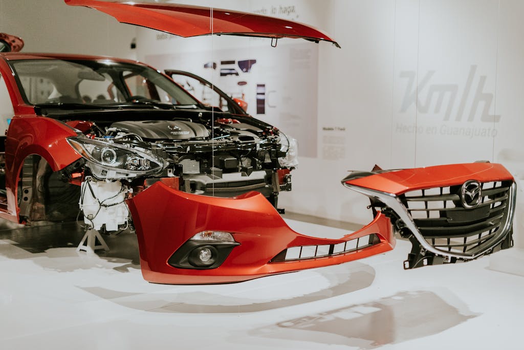 Imagen actual: Explore a detailed view of a partially disassembled red Mazda 3 showcased at an auto exhibition.