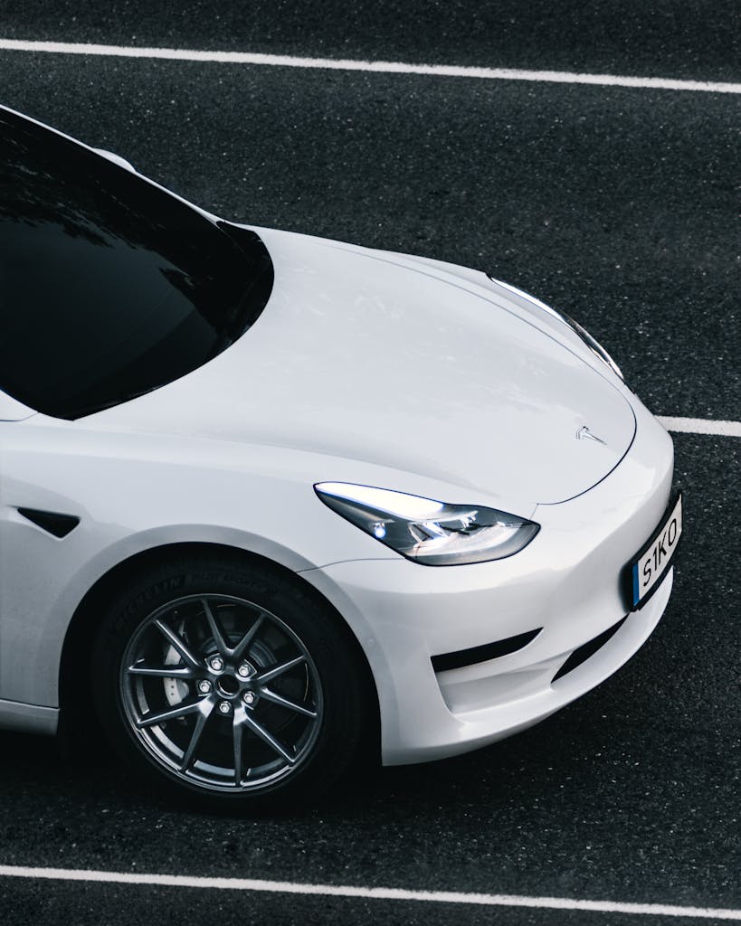 Imagen actual: Top view of a sleek white Tesla electric car driving on a city street in Germany.