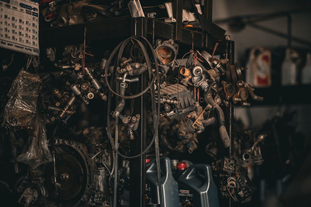 Imagen actual: A cluttered auto workshop with various mechanical parts hanging in a dimly lit environment.