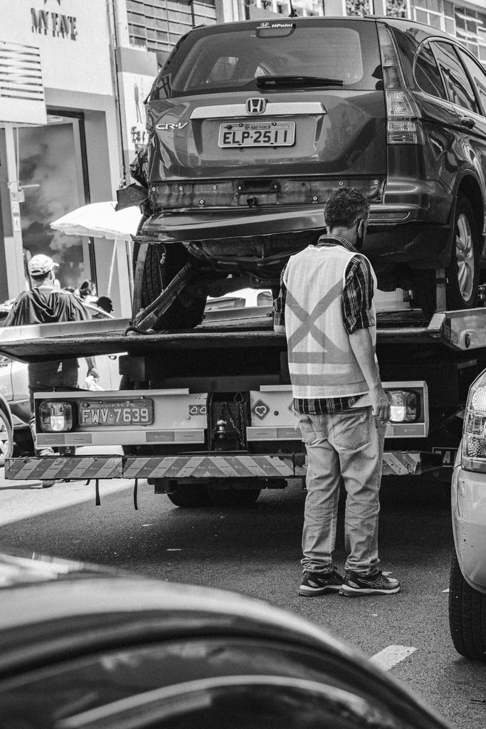 Imagen actual: Grayscale image of a tow truck loading a vehicle on a busy street in São Paulo.